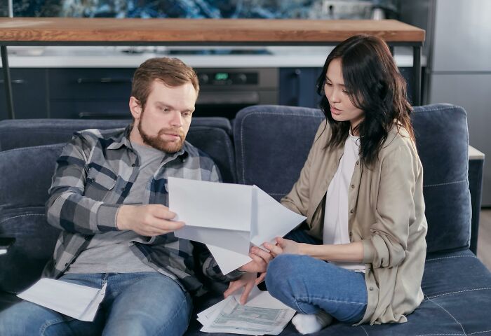 Couple reviewing bills on a couch while managing frugal finances