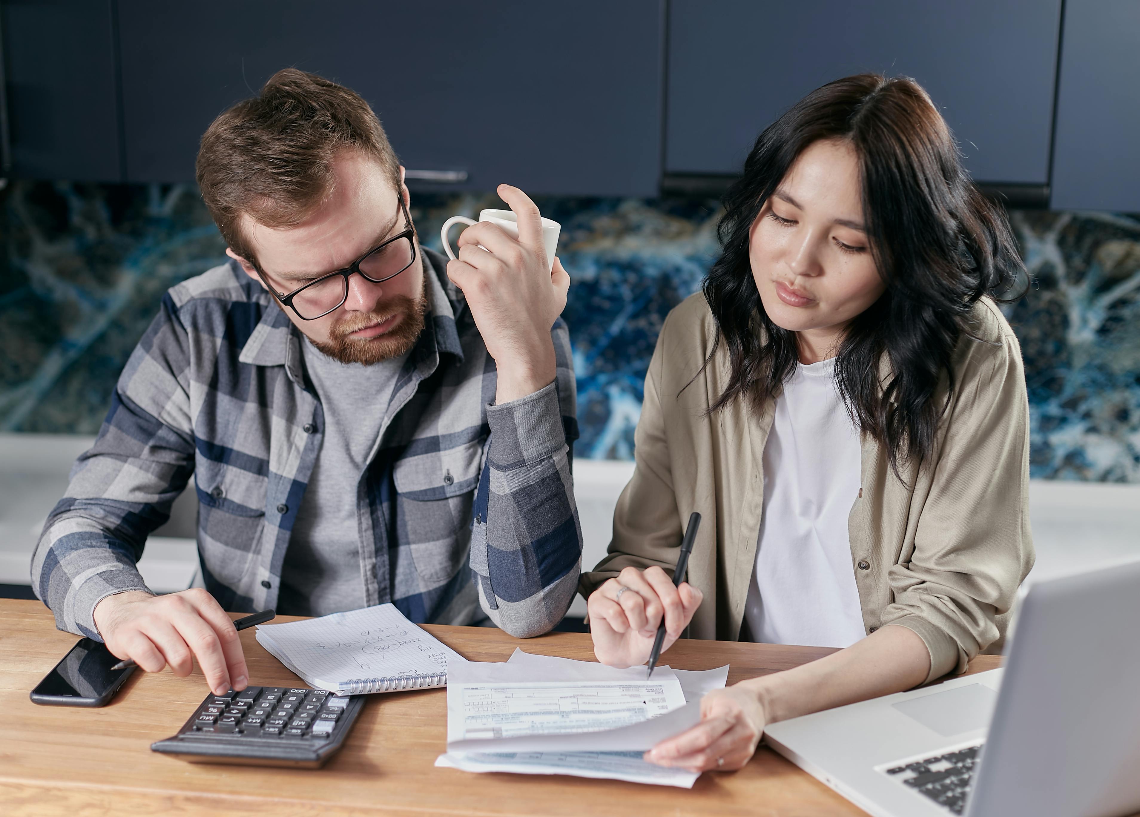Couple looking stressed while calculating bills and finances