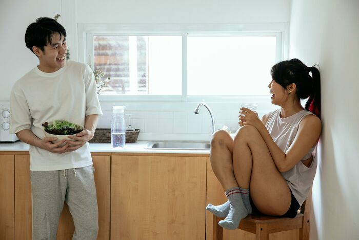 Couple sharing a light moment in the kitchen with salad and water