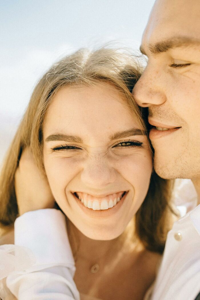 Happy couple smiling closely embracing in bright natural light