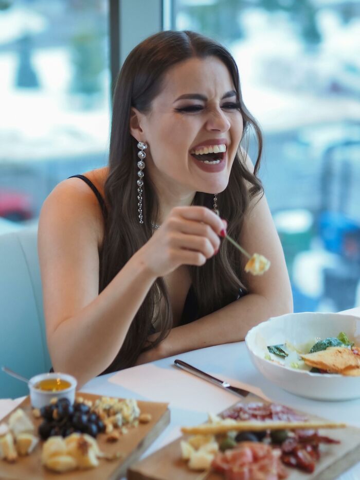 Woman laughing joyfully while eating at a restaurant table
