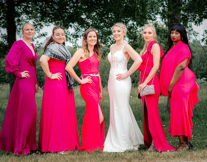 Bride posing with bridesmaids in bright pink dresses outdoors