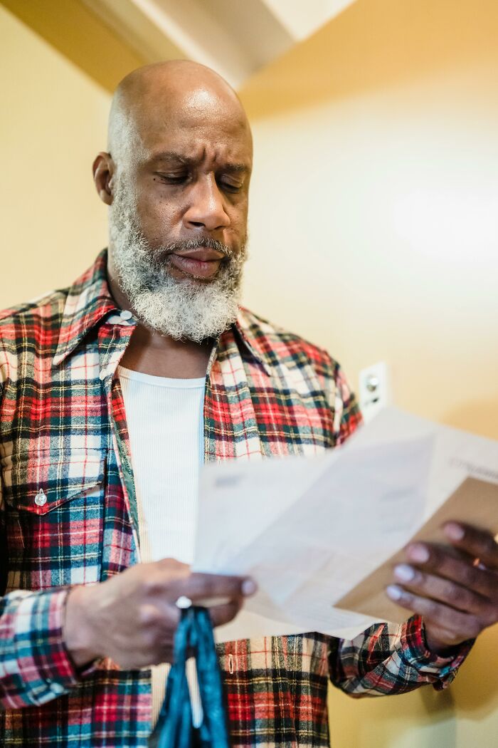 Man with beard reading documents indoors looking concerned