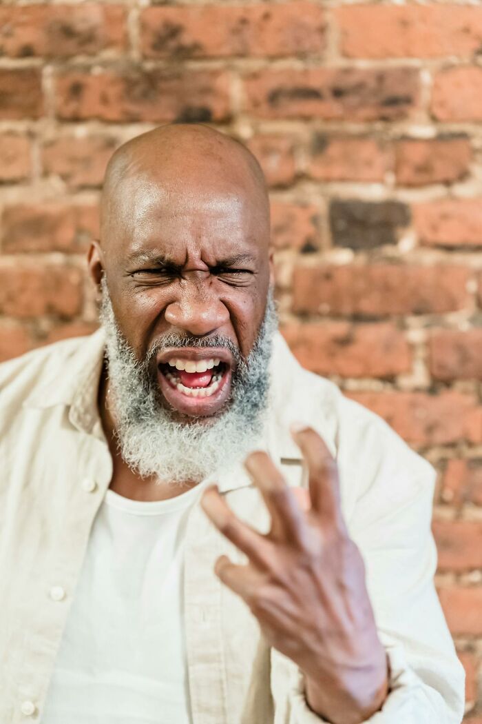 Angry man expressing frustration against brick wall