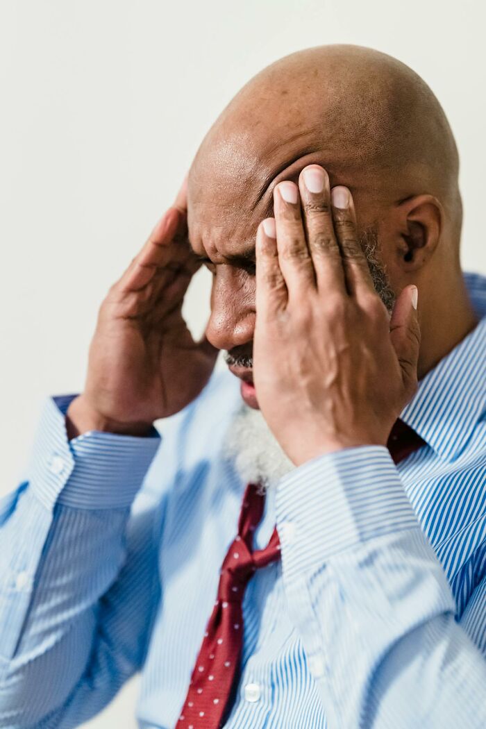 A man with hands on his temples, showing stress from wedding drama stories.