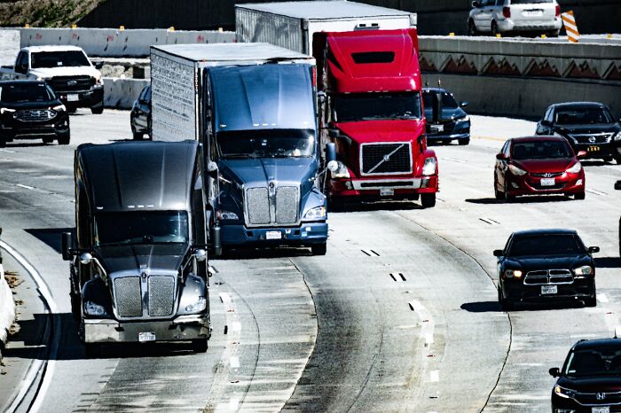 Semi trucks and cars driving on a busy highway with multiple lanes