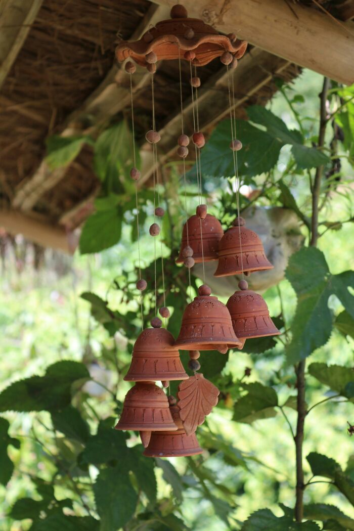 Decorative clay wind chimes hanging outdoors among leaves
