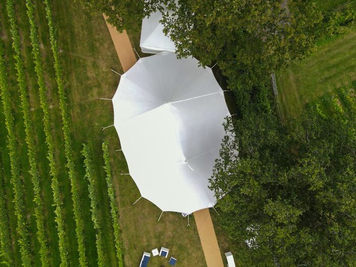 Aerial view of a white wedding tent among greenery at outdoor wedding venue