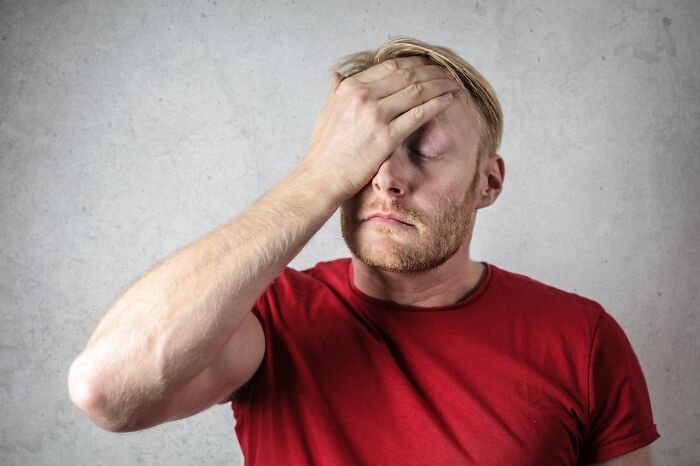 Man in red shirt frustrated with hand on face in boneheaded comments context