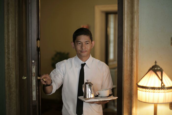 Waiter holding tray with teapot and cup demonstrating frugal service ideas