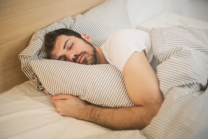 Man sleeping peacefully in bed illustrating laziness saving from disaster