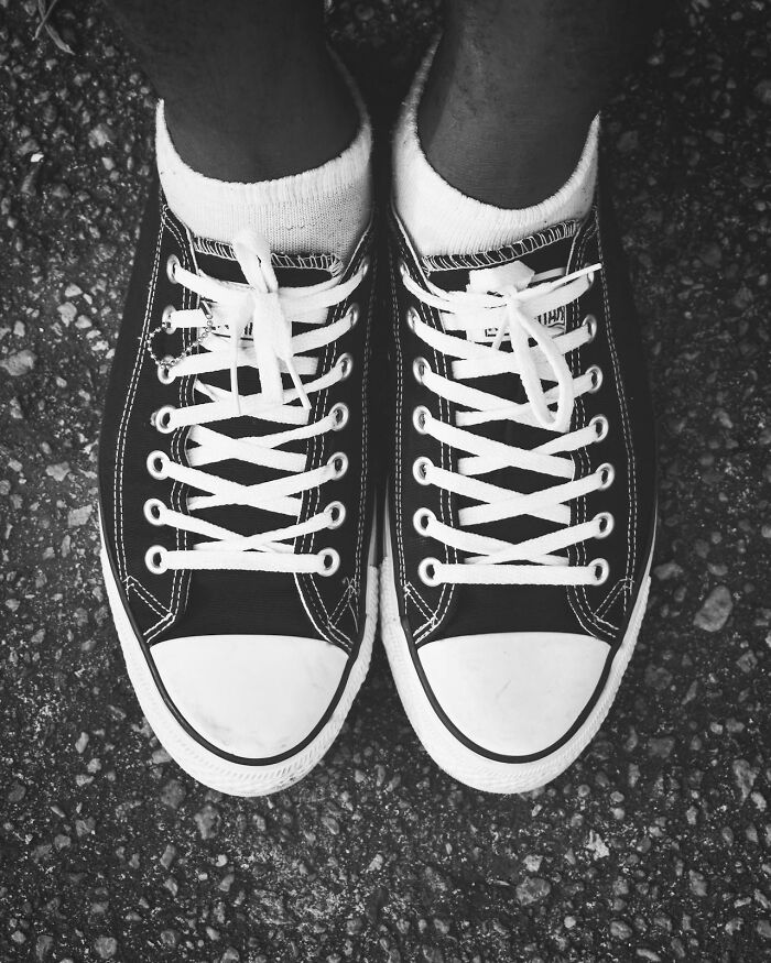 Top view of black and white sneakers with white socks on asphalt
