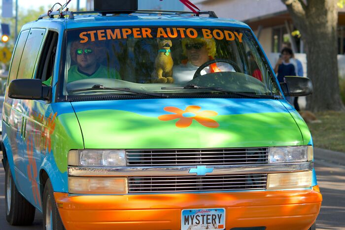 Scooby-Doo themed van with mystery machine colors and two people inside representing Saturday morning cartoons