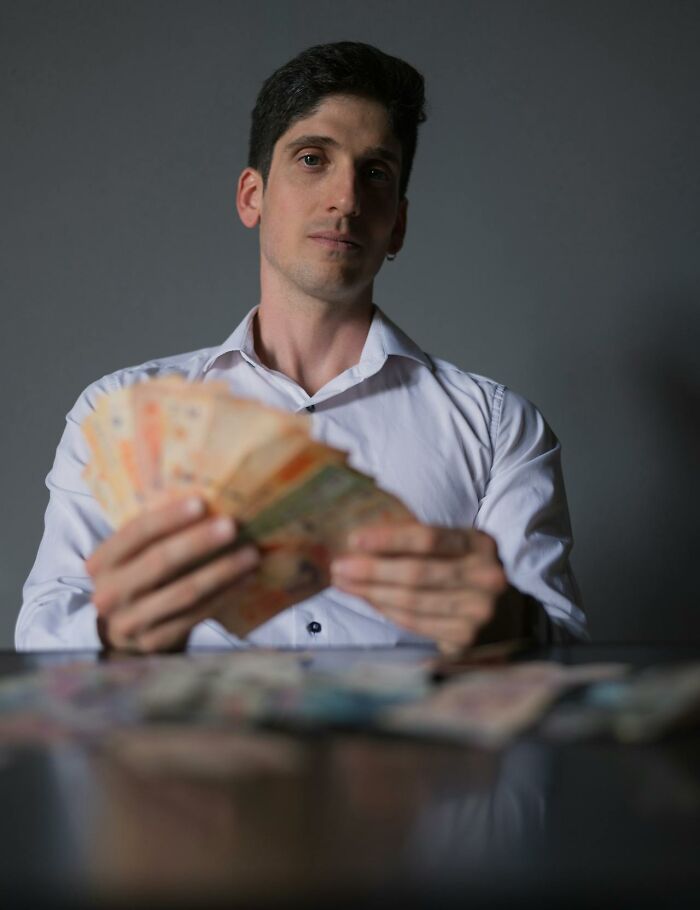 A man in a white shirt counting a stack of money, highlighting financial wedding drama stories.