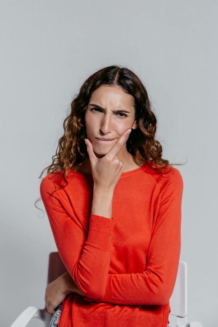 Thoughtful woman in orange sweater memorizing random facts