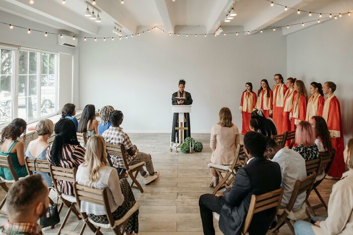 Group meeting with speaker and choir in robes illustrating cult escape support group
