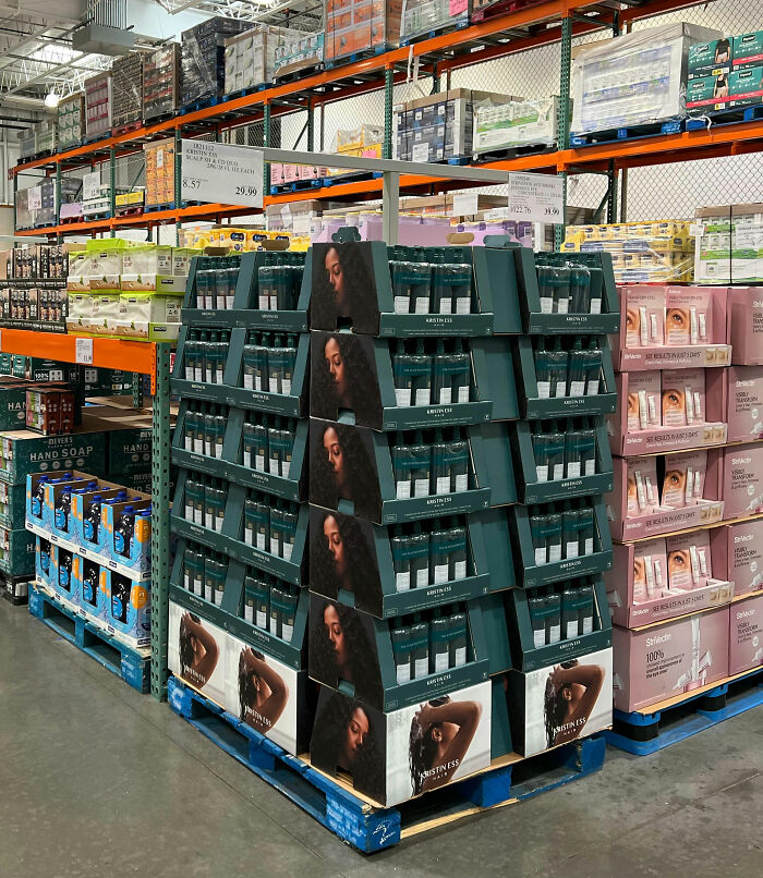 Bulk Kristin Ess hair products display in a warehouse store, showcasing habits that save money by buying in quantity.