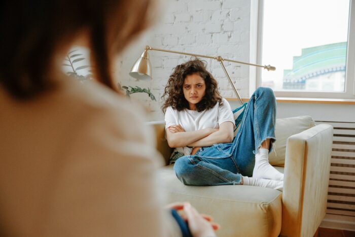 Angry young woman sitting with arms crossed on couch
