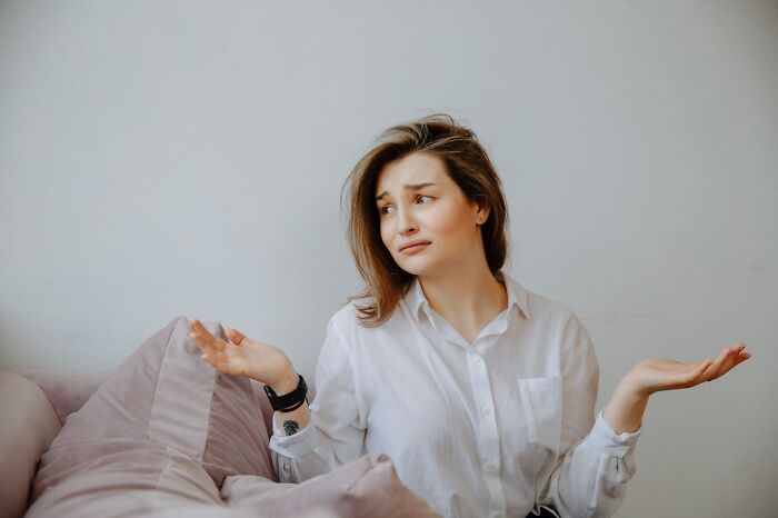 Woman shrugging confused on couch for boneheaded comments article