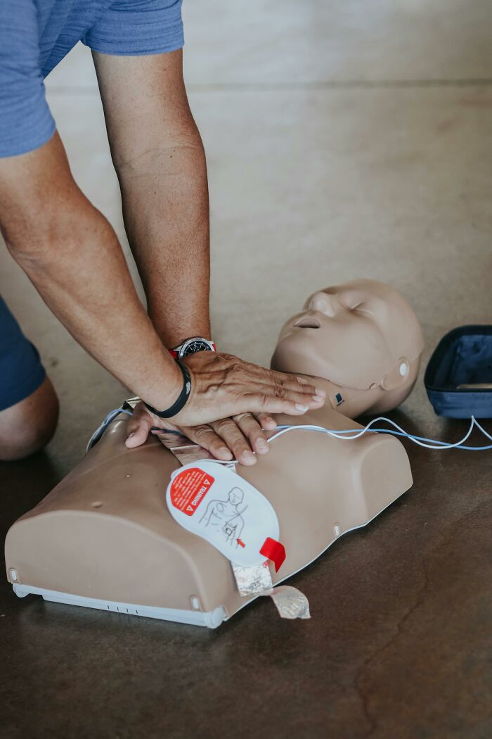 A person performs chest compressions on a CPR mannequin, demonstrating a very creepy medical training exercise.