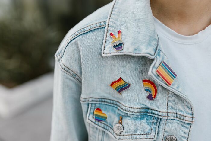 Denim jacket with rainbow pride pins closeup