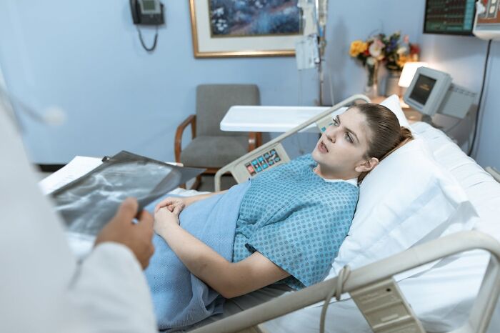 A patient in a hospital bed looks worried as a doctor shows her an X-ray. Could this be a glitch in the matrix?