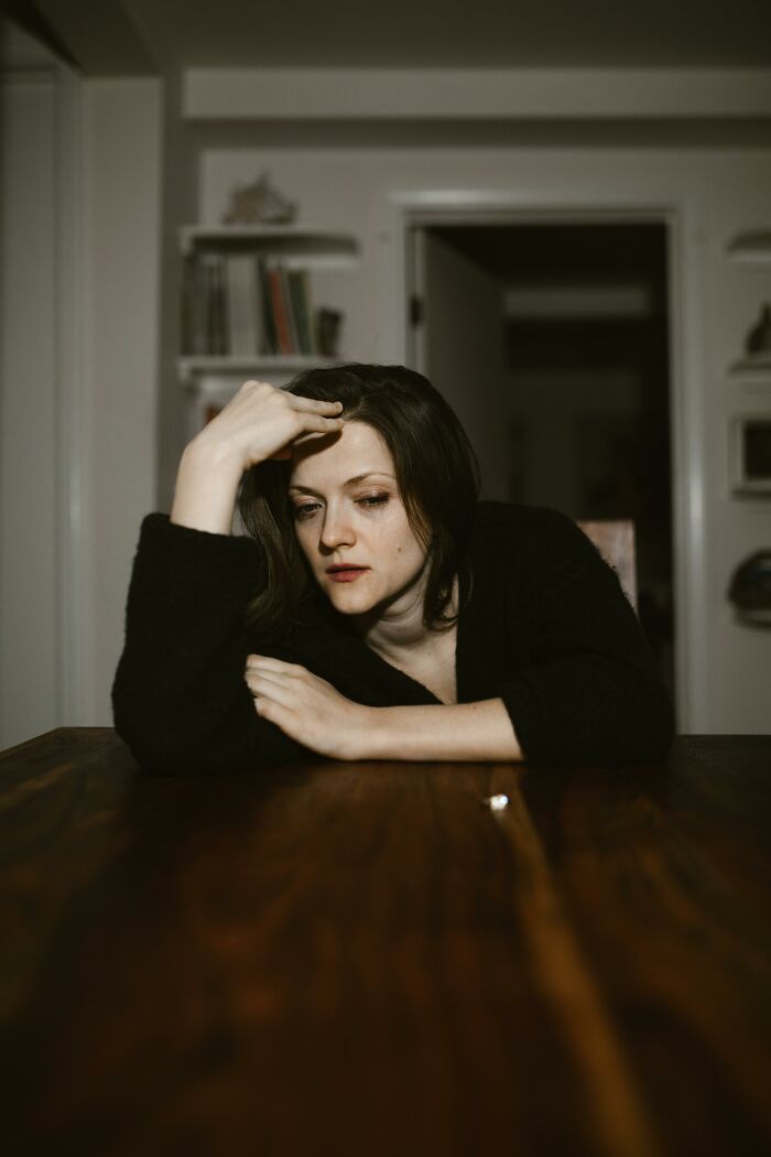 Woman looking distressed at table after escaping a cult