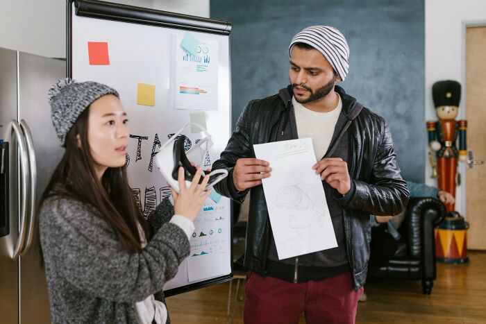 Young man showing drawing to woman in casual creative workspace
