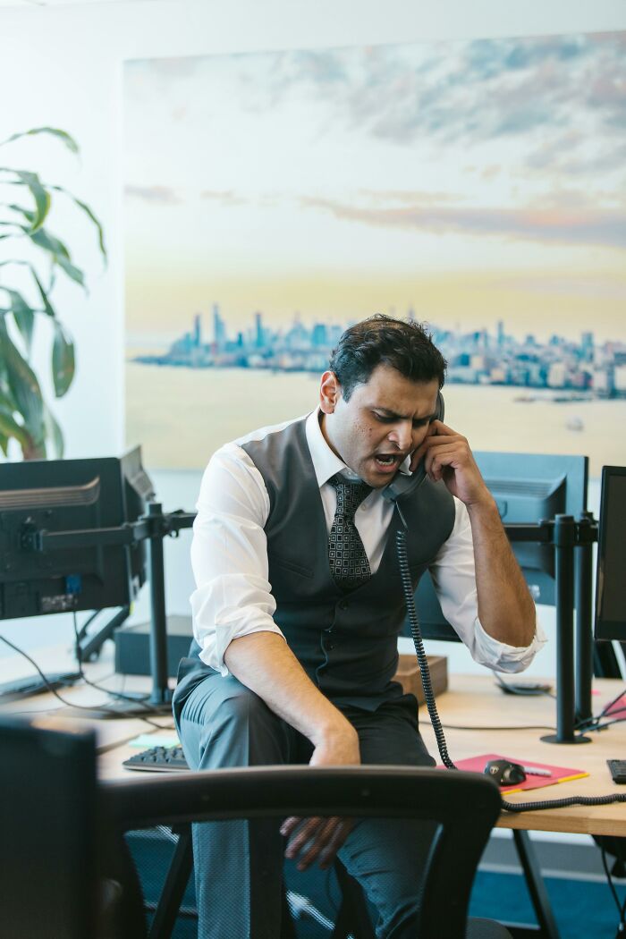 Frustrated office worker talking on phone in corporate setting
