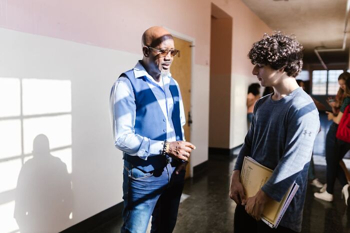 Teacher talking to student in hallway, laziness saving people interaction