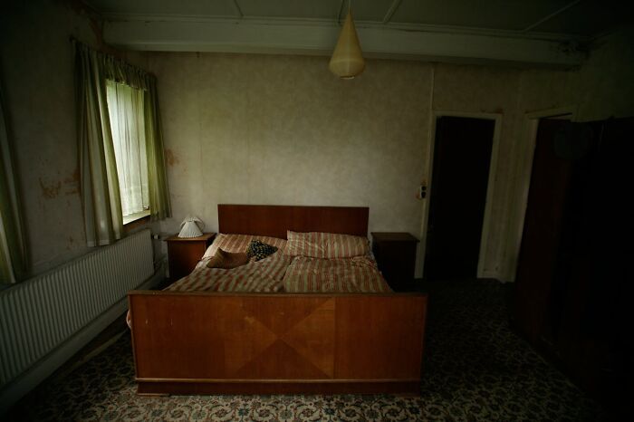 Dimly lit hotel bedroom with an unmade bed and vintage decor