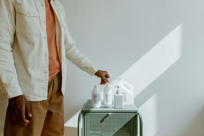 Person dispensing liquid from container on table representing frugal product use