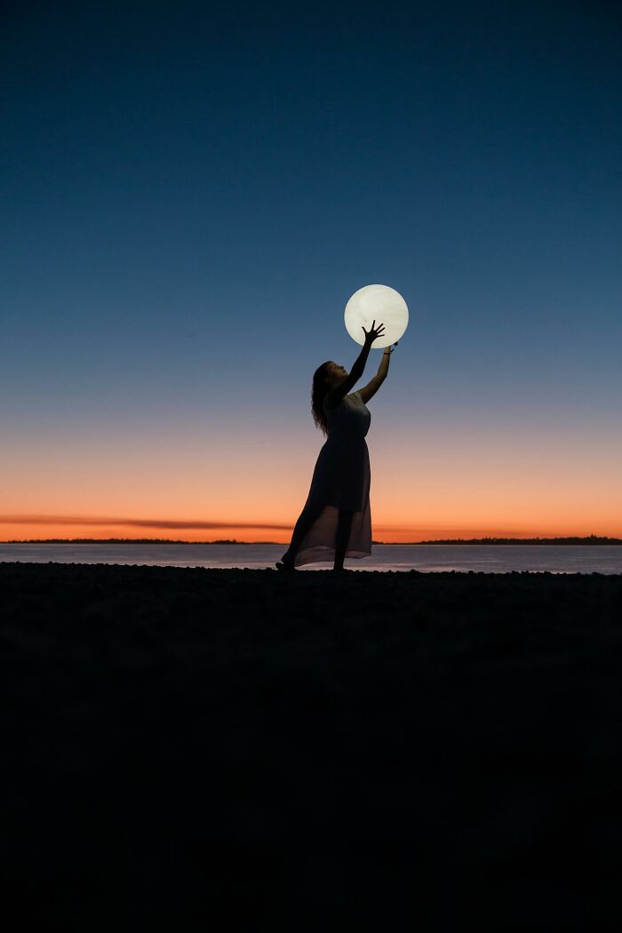 Silhouette of woman holding glowing orb at sunset