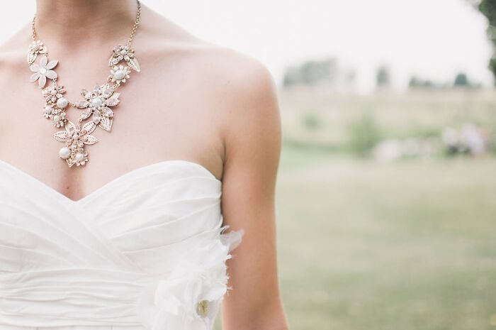 Closeup of bride in white dress wearing floral necklace wedding photography