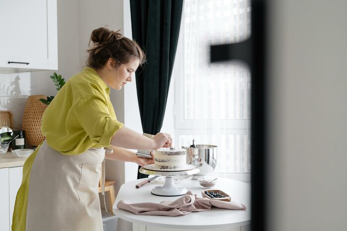 Woman decorating cake in kitchen inspired by exes unhinged stories