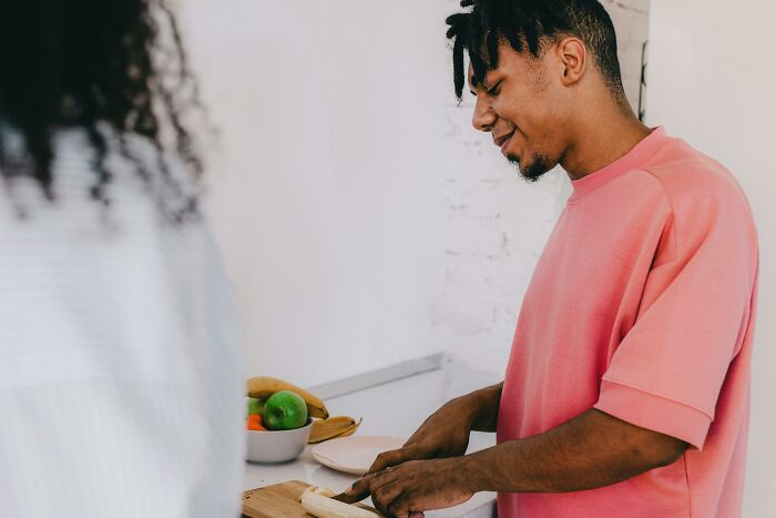 Man smiling while cutting banana in kitchen