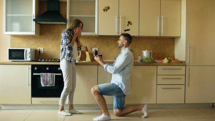 Man proposing to woman in kitchen with engagement ring during special moment