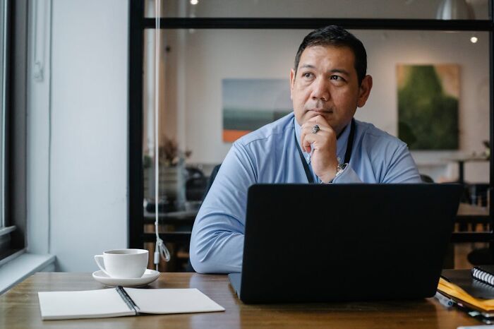 Man pondering thoughtfully at laptop, showing laziness preventing disaster