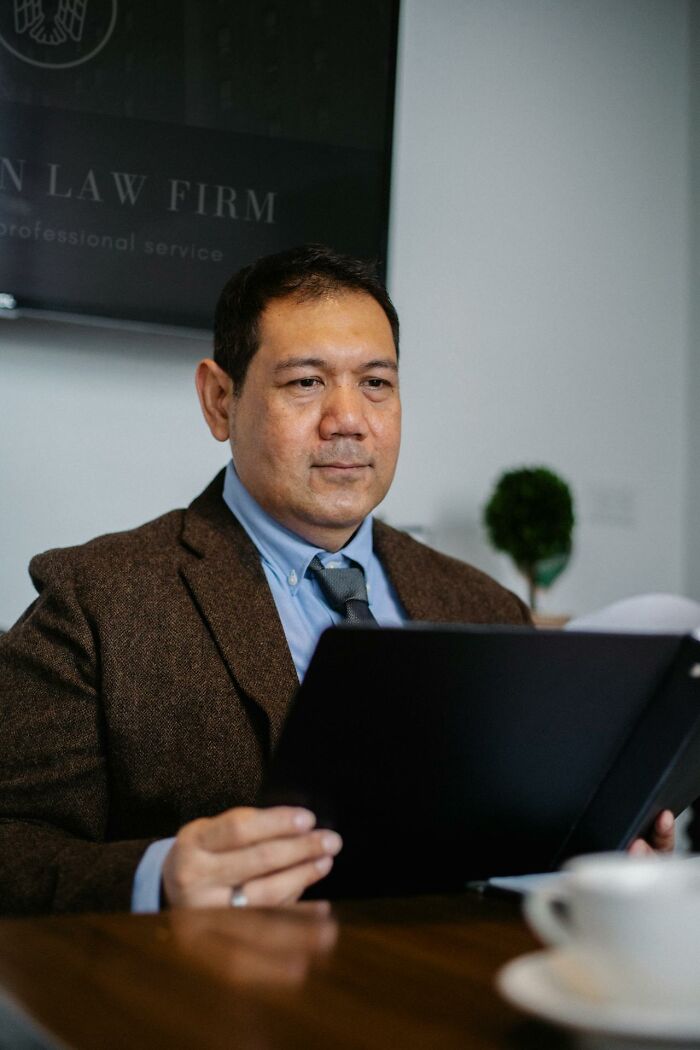 Male lawyer in brown jacket reviewing documents at law firm desk