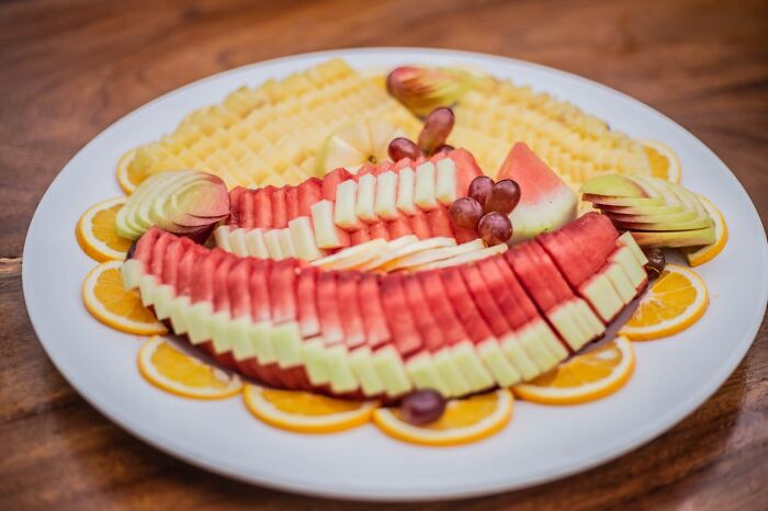Plate of sliced watermelon, apples, grapes, and oranges arranged for a wedding reception fruit platter