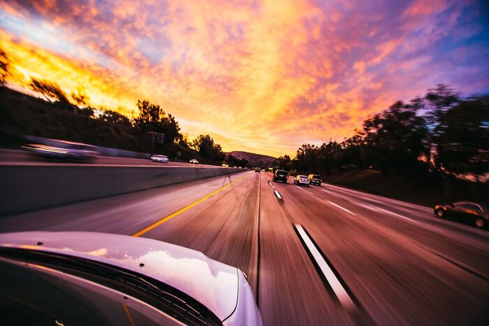 Highway with fast traffic under a vibrant sunset sky