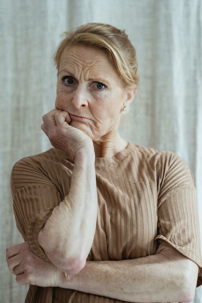 An older woman with a pensive expression, representing the emotional aspect of wedding drama stories.