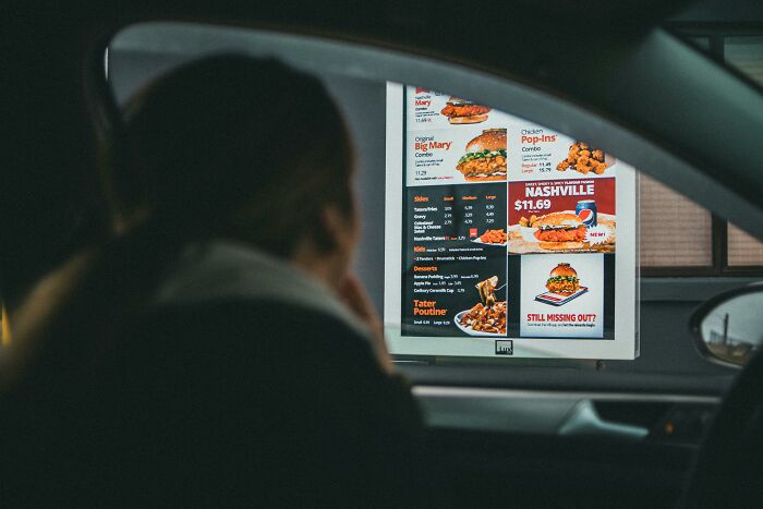 Person looking at fast food drive-thru menu from inside a car