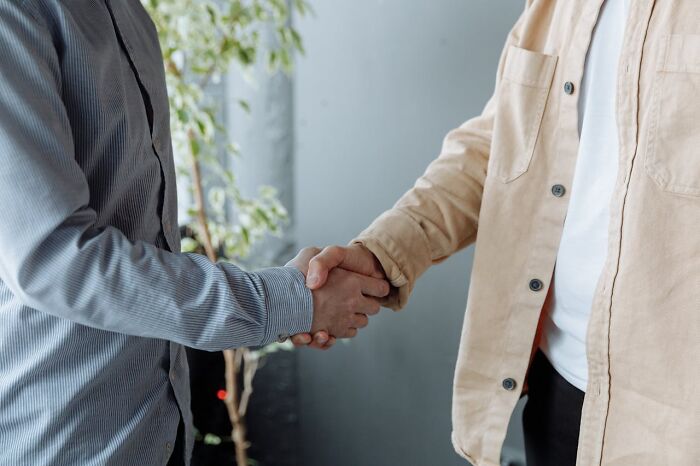 Two people shaking hands, signifying trust and agreement, in contrast to deeply immoral acts.