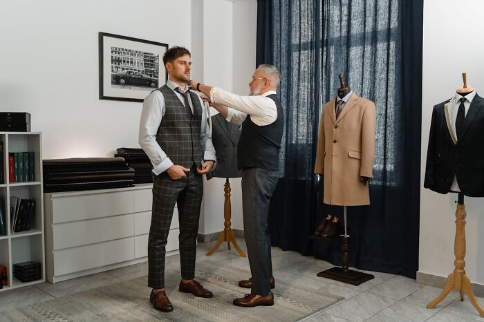 Tailor adjusting suit on man highlighting laziness saving from disaster