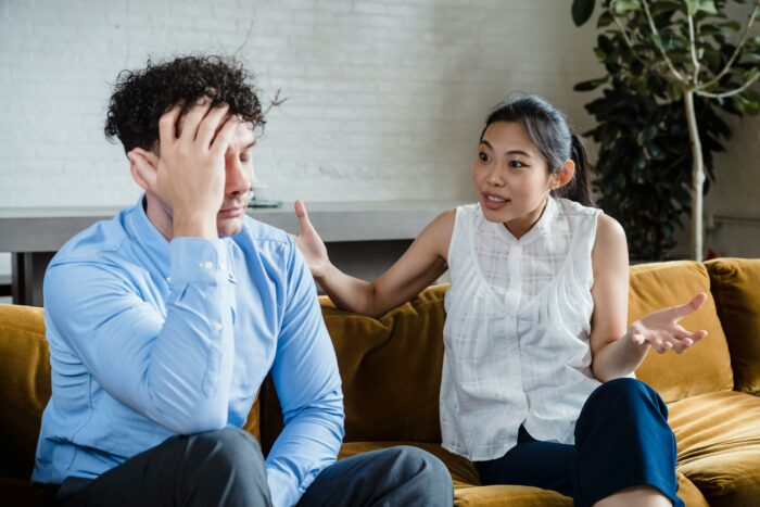 Woman demanding boyfriend propose again while he looks stressed on couch