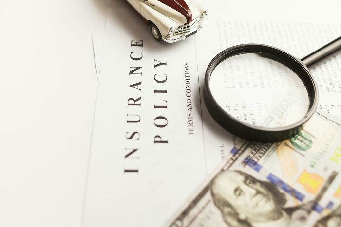 An insurance policy, magnifying glass, a car toy, and money. Habits people deem expensive can save money.