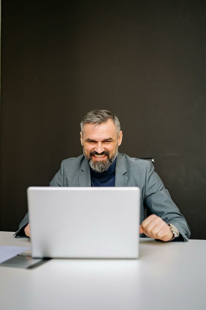 Smiling man in suit working on laptop, laziness saving people success