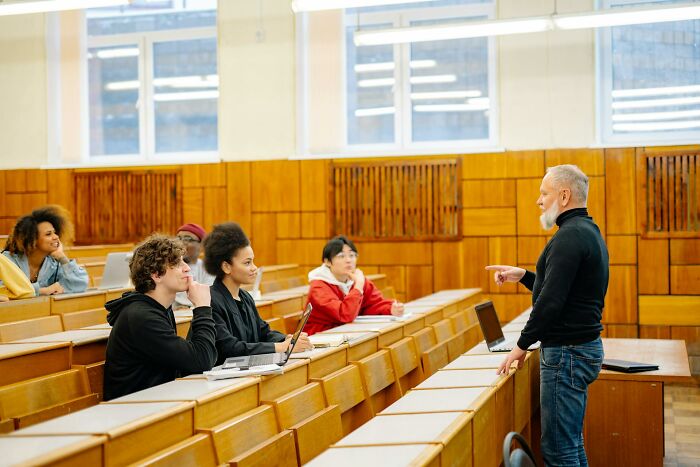 Teacher engaging students in a lecture highlighting laziness avoiding disaster