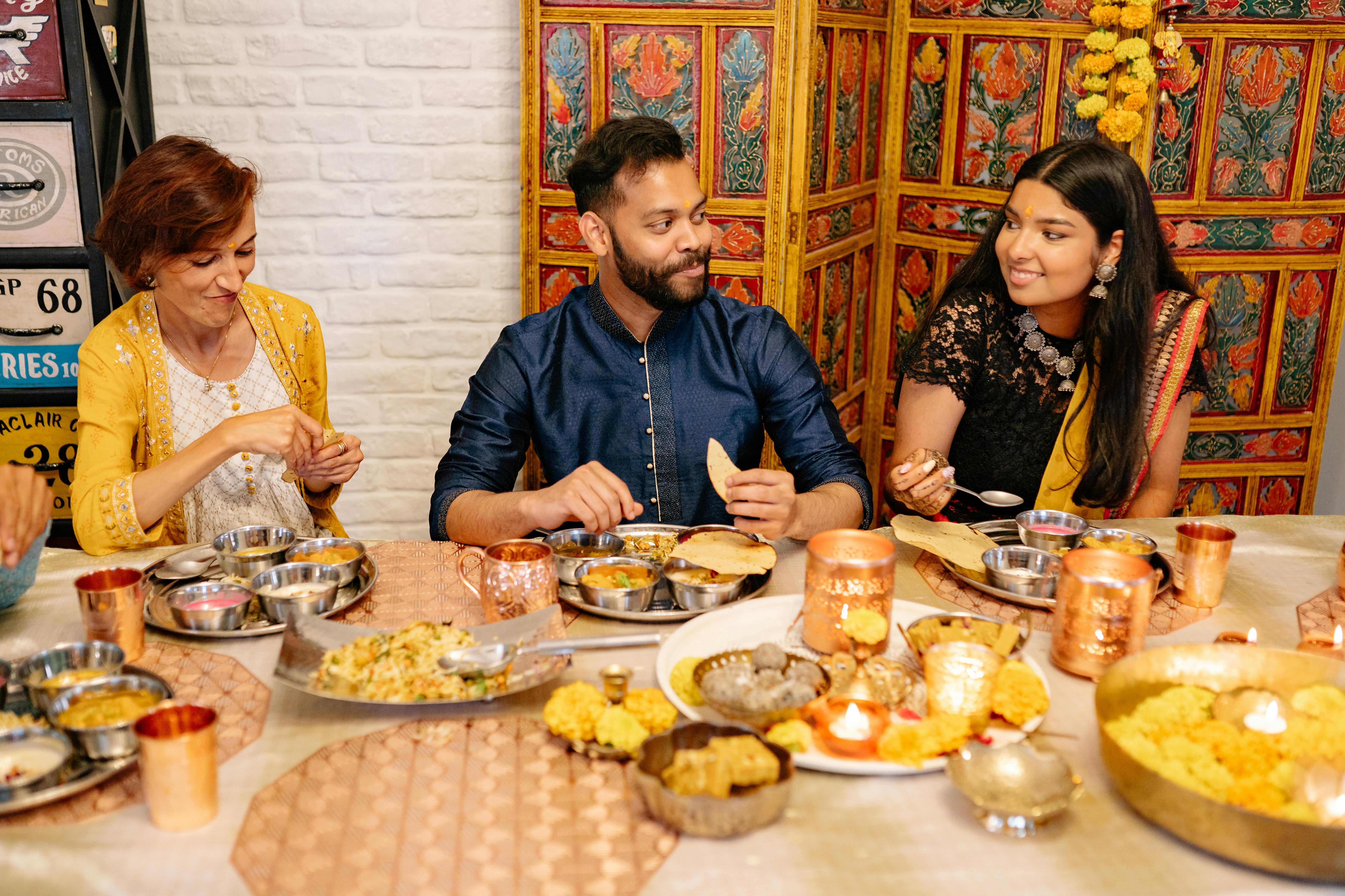 Group enjoying Indian meal and conversation at festive table Group enjoying Indian meal and conversation at festive table